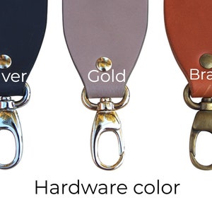 May include: Three leather straps with different colored hardware. The strap on the left has silver hardware, the middle strap has gold hardware, and the strap on the right has brass hardware. The text "Hardware color" is written below the straps.