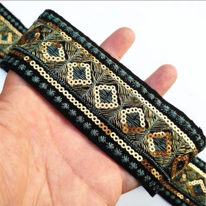 May include: Black velvet trim with gold and teal embroidery and sequins. The trim features a geometric pattern.