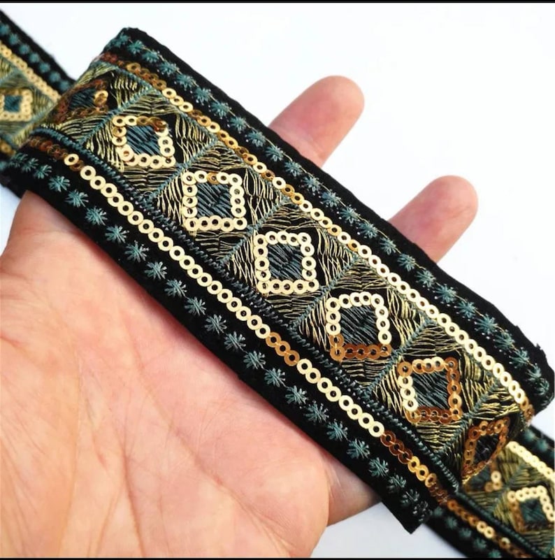 May include: Black velvet trim with gold and teal embroidery and sequins. The trim features a geometric pattern.