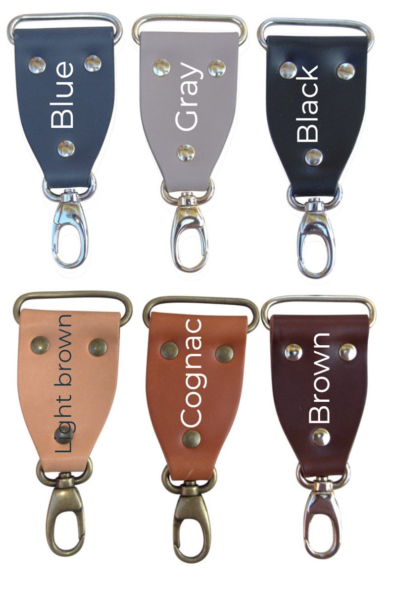 Pode incluir: Seis chaveiros de couro de diferentes cores com fechos de metal. As cores s&atilde;o azul, cinza, preto, castanho claro, conhaque e castanho. Cada chaveiro tem o nome da cor escrito nele.