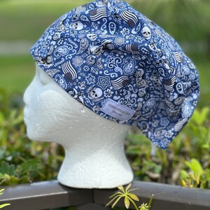 Peut inclure: Un bonnet de travail bleu et blanc à motifs de crânes, de motifs paisley et de drapeaux américains. Le bonnet est sur une tête de mannequin blanche. Le texte "COSMICBOHOART Etsy.com" est sur le bonnet.
