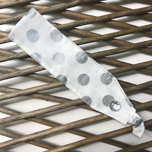 May include: White headband with silver polka dots and a silver button.