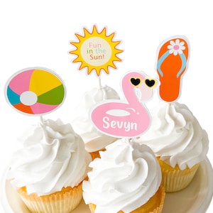May include: Four cupcakes decorated with summer-themed toppers. The toppers include a pink flamingo with the name "Sevyn", a beach ball, a yellow sun with the text "Fun in the Sun!" and a flip-flop.