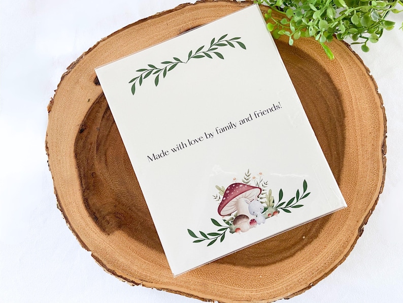 Puede incluir: Una tarjeta blanca con el texto "Made with love by family and friends!" se muestra sobre una superficie de madera. La tarjeta presenta una ilustraci&oacute;n de acuarela de setas y un peque&ntilde;o animal. Acentos de hojas verdes enmarcan la parte superior e inferior.