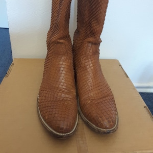 May include: A pair of brown leather cowboy boots with a snakeskin pattern.