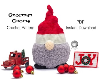 May include: Crochet pattern for a gray gnome wearing a red and white hat. The gnome is sitting on a white surface with red ornaments and a red toy truck. The pattern is available as an instant PDF download. The text "Gnorman Gnome Crochet Pattern" and "PDF Instant Download" is visible in the image.