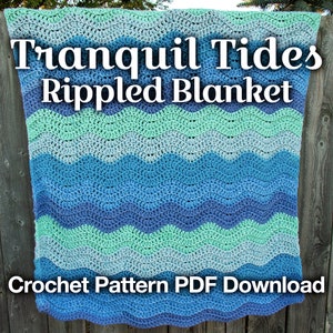 May include: A crocheted blanket with a wavy pattern in shades of blue and green. The blanket is held up by a person, with a wooden fence and trees in the background.