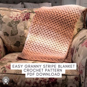 May include: A handmade, crocheted blanket in a granny stripe pattern, draped over a floral armchair. The blanket features a gradient of colors, transitioning from light cream to shades of peach and brown. The text on the image reads: EASY GRANNY STRIPE BLANKET CROCHET PATTERN PDF DOWNLOAD.