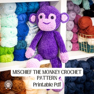 May include: A plush, purple crochet monkey with light purple accents on its face, ears, hands, and feet. The monkey is sitting on a shelf in front of a backdrop of colorful yarn skeins. The text "MISCHIEF THE MONKEY CROCHET PATTERN Printable Pdf" is displayed below.