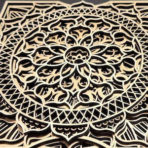 May include: A layered wooden mandala with intricate geometric patterns. The design features a central floral motif surrounded by concentric circles and detailed cutouts. The natural wood color contrasts with the dark background, highlighting the artwork's depth and complexity.