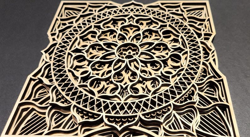 May include: A layered wooden mandala with intricate geometric patterns. The design features a central floral motif surrounded by concentric circles and detailed cutouts. The natural wood color contrasts with the dark background, highlighting the artwork's depth and complexity.