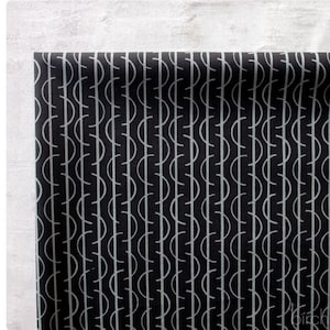 May include: A black fabric featuring a repeating pattern of vertical lines intersected by light gray semicircles arranged in a column. The design consists of thin, uniform lines creating a geometric motif across the dark surface of the textile material.