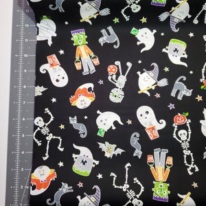 K&ouml;nnte beinhalten: Schwarzer Stoff mit einem Halloween-Motiv mit Geistern, Skeletten, Mumien, Flederm&auml;usen, Katzen und Sternen. Der Druck ist in verschiedenen Farben, darunter Orange, Gr&uuml;n, Wei&szlig; und Lila.