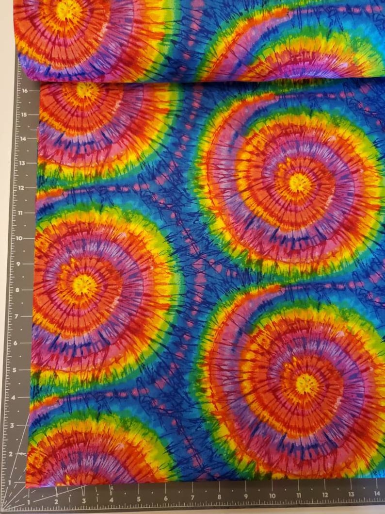 Pode incluir: Tecido tie-dye multicolor com um padr&atilde;o de redemoinho de rosa, vermelho, amarelo, laranja, verde e azul.