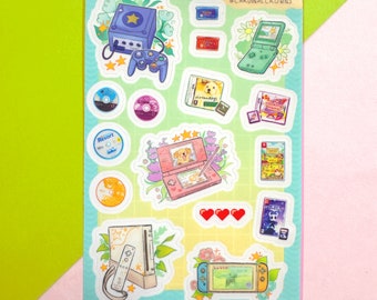 以下が含まれることがあります： 様々なゲームをテーマにしたイラストが描かれたステッカーシート。紫色のゲーム機、緑色の携帯ゲーム機、ピンク色の携帯ゲーム機、ゲームカートリッジ、ゲームディスクが含まれています。シートには水色の縁取りがあり、「CARDINAL CUSACK @CARDINALCROWNS」の文字が書かれています。
