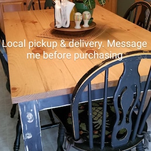 May include: A rustic wooden table with black painted legs and a distressed finish. The table is set with four black chairs with woven seats. The table is decorated with a potted plant, napkins, and salt and pepper shakers. Local pickup & delivery. Message me before purchasing.