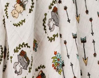 May include: Three white muslin baby swaddles with different patterns. One swaddle has a repeating pattern of woodland animals wearing crowns. Another swaddle has a repeating pattern of arrows. The third swaddle has a repeating pattern of arrows with different colored tips.
