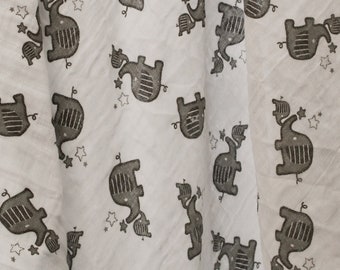 May include: White muslin baby blanket with a repeating pattern of gray elephants carrying stars. The elephants are stylized and have a simple design.