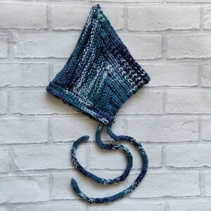 May include: A blue and white striped knitted hat with a long tie. The hat is made of a soft, warm yarn and has a unique, pointed shape.