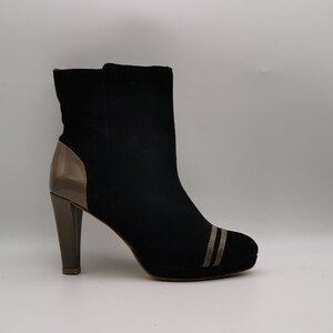 Peut inclure: Bottines en daim noir avec un talon en cuir marron et deux bandes dorées sur l'orteil.