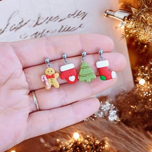 Può includere: Quattro paia di orecchini a tema natalizio con un uomo di pan di zenzero, un guanto, un albero di Natale e una calza. Gli orecchini sono argentati con accenti rossi, verdi e bianchi.