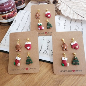 Può includere: Tre set di orecchini a tema natalizio su cartoncino marrone. Ogni set include un omino di pan di zenzero, un guanto rosso, una calza e un albero di Natale. Gli orecchini sono fatti a mano con amore.