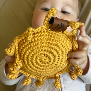 May include: A crocheted yellow sun toy with a brown leather tag that says "The Little Seed".