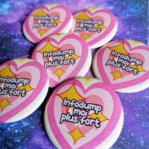 Peut inclure: Cinq boutons en forme de cœur rose et blanc avec le texte "Infodump moi plus fort" en noir et jaune. Les boutons ont une finition brillante et sont disposés en cercle.