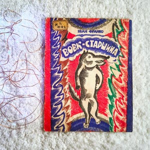 Puede incluir: Libro infantil vintage con una portada colorida. La portada presenta una ilustración de lobo de dibujos animados en blanco y negro, sobre un fondo rojo y azul. El título está en una fuente estilizada.