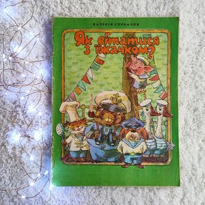 Peut inclure: Un livre pour enfants vintage avec une couverture verte. L'illustration montre des animaux de dessins animés en tenues de marins, dont un cochon, un castor, un chien et des canards. Le titre du livre est dans une langue étrangère.