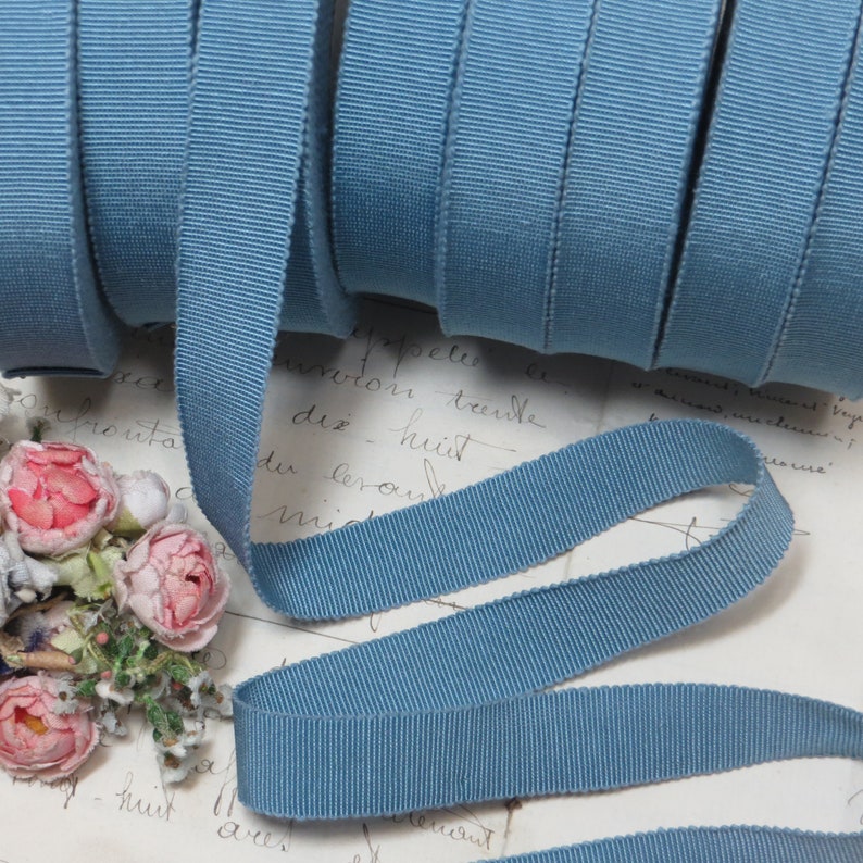 May include: A roll of light blue grosgrain ribbon. The ribbon is 1.2 cm wide and has a subtle ribbed texture.