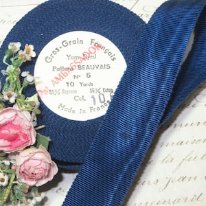 May include: A spool of deep blue grosgrain ribbon with a white label that reads "Gros-Grain Français Yarn Dyed Pattern BEAUVAIS No. 5 10 Yards 44% Rayonne 56% Coton Col. 108 Made in France".