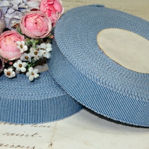 May include: Two spools of blue grosgrain ribbon. The ribbon is a light blue color and has a ribbed texture.