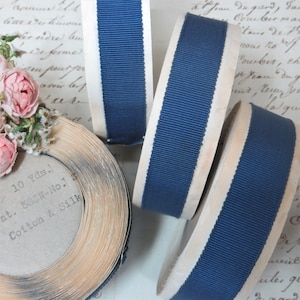 May include: Three spools of navy blue grosgrain ribbon with white edges. The spools are labelled "10 Yds.", "at. 583W-No.1", and "Cotton & Silk".