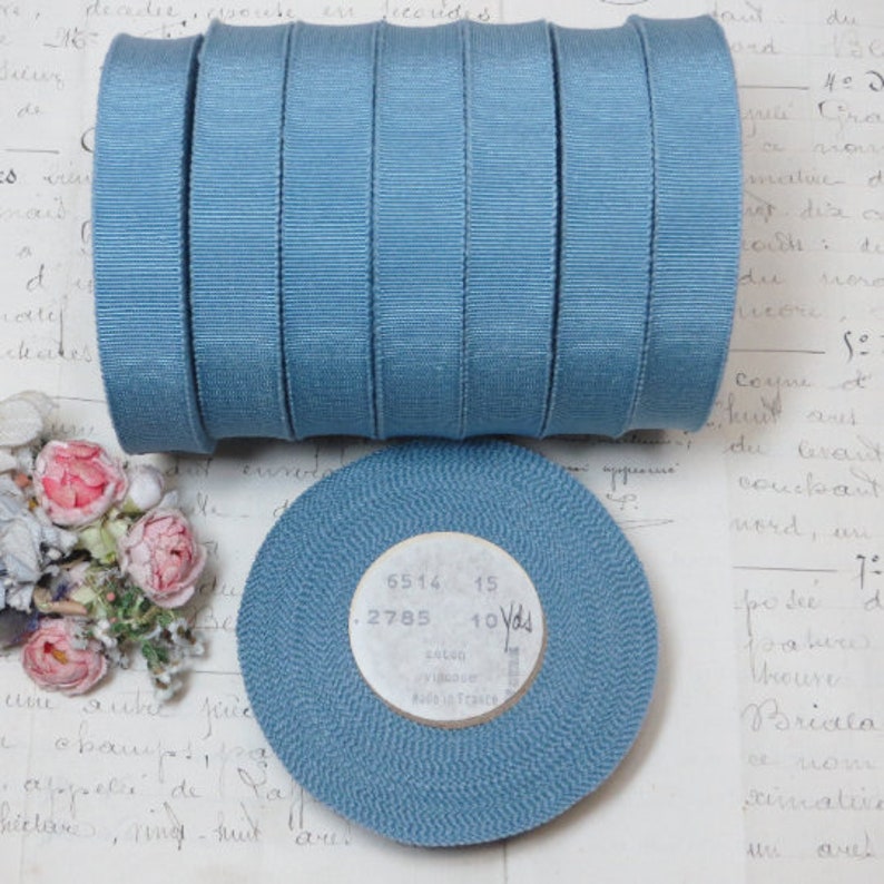 May include: A roll of 10 yards of blue grosgrain ribbon. The ribbon is 1/2 inch wide and is made of cotton and viscose. The label on the ribbon reads "6514 15 .2785 10 Yds Cotton Viscose Made in France".