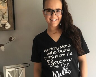 May include: Black v-neck t-shirt with white text that reads "Working Moms Who Pump Bring Home The Bacon and the Milk".