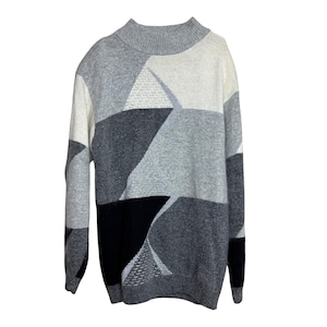 Puede incluir: Un suéter con estampado geométrico en tonos grises, negros y blancos. El suéter tiene cuello alto y mangas largas. El diseño está compuesto por varias formas y texturas, creando un look moderno y elegante.