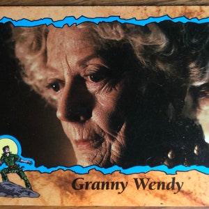 Puede incluir: Una tarjeta coleccionable con el texto "Granny Wendy" que presenta un primer plano del rostro de una anciana. La tarjeta tiene un borde azul y una imagen de dibujos animados de un personaje. El fondo es oscuro.