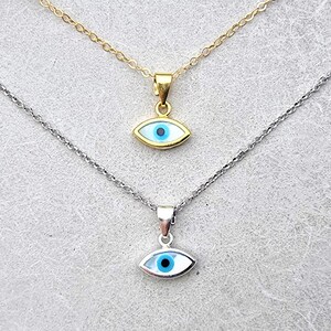 May include: Two silver necklaces with blue evil eye pendants. The top necklace has a gold chain and the bottom necklace has a silver chain.