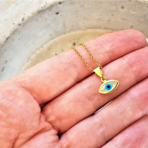 May include: Gold chain necklace with a small blue evil eye pendant.