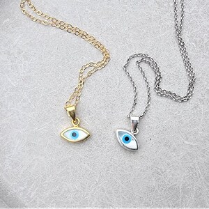 May include: Two silver necklaces with blue evil eye pendants. One necklace is gold and the other is silver.