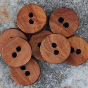 May include: A set of eight wooden buttons with two black holes each. The buttons are a light brown color and have a natural wood grain.
