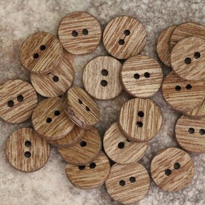 May include: A collection of wooden buttons with a natural wood grain finish. The buttons are round and have two holes each.