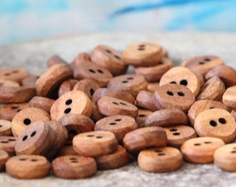 May include: A pile of brown wooden buttons with two holes each. The buttons are arranged in a random pattern on a light brown surface.