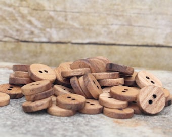 May include: A pile of wooden buttons with two holes each. The buttons are a light brown colour and have a natural wood grain.