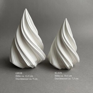 Może przedstawiać: Dwie białe ceramiczne rzeźby w kształcie spirali. Większa rzeźba jest oznaczona jako "GROB" i ma 12,5 cm wysokości i 9 cm średnicy. Mniejsza rzeźba jest oznaczona jako "KLEIN" i ma 10,5 cm wysokości i 7,5 cm średnicy.