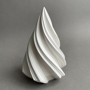 Może przedstawiać: Biała ceramiczna rzeźba o spiralnym, wirującym wzorze. Rzeźba ma kształt stożka i gładkie, błyszczące wykończenie.