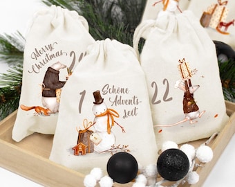 May include: Three off-white fabric drawstring bags featuring Christmas illustrations. One bag shows a bear and squirrel with "Merry Christmas", another a snowman with "Schöne Adventszeit", and the third a mouse holding a gift with the number 22.