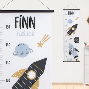 Könnte beinhalten: Ein weißer Wachstumskalender mit schwarzem Rahmen, der eine Rakete, einen Planeten und einen Sternschnuppen zeigt. Der Kalender ist mit "FINN" beschriftet und enthält das Datum "25.08.2018".