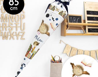 Könnte beinhalten: Ein weißer und blauer Schultüte mit einem verspielten Eulen-Design und dem Namen "Milan" darauf gedruckt. Die Tüte ist mit Büchern und einem blauen und weißen Spritzmuster verziert. Die Tüte ist 85 cm hoch.
